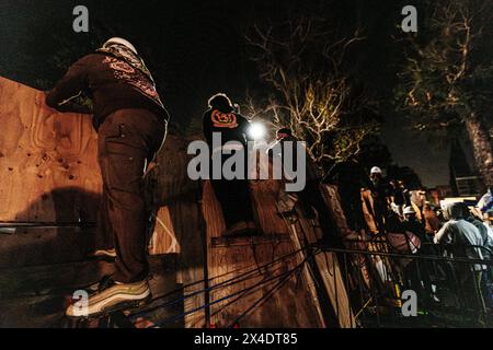 Pro-Palestinian protesters look on at area police forces from the encampment built in front of Royce Hall at UCLA. Stock Photo