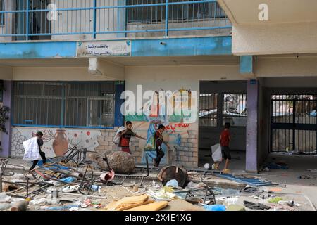 Khan Younis. 2nd May, 2024. Children walk past a school building affiliated with the United Nations Relief and Works Agency for Palestine Refugees in the Near East (UNRWA) in the southern Gaza Strip city of Khan Younis, on May 2, 2024. Credit: Rizek Abdeljawad/Xinhua/Alamy Live News Stock Photo