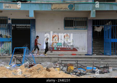 Khan Younis. 2nd May, 2024. Children walk past a school building affiliated with the United Nations Relief and Works Agency for Palestine Refugees in the Near East (UNRWA) in the southern Gaza Strip city of Khan Younis, on May 2, 2024. Credit: Rizek Abdeljawad/Xinhua/Alamy Live News Stock Photo