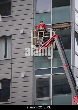 Worker in elevated cherry picker platform undertaking reactive repair ...