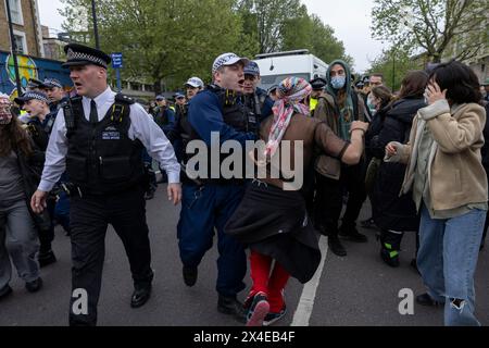A coach sent to collect asylum seekers and take them to the Bibby Stockholm barge surrounded by protesters in Peckham south London England, UK Stock Photo