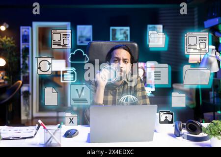 Portrait of man in home office doing business tasks on laptop, online connectivity concept. Freelancer using augmented reality tech to interact with files on notebook system, close up on icons Stock Photo