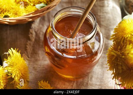 A jar of dandelion flower syrup on a table Stock Photo