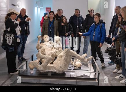 Tourism Pompeii Italy - tourists looking at the casts of the dead bodies of adults and children; Pompei World Heritage site, Campania Italy Stock Photo