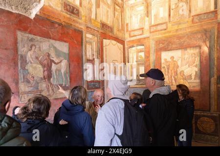 Pompeii tourists; A tour guide giving a guided tour to tourists of the frescoes in The House of the Vettii; Pompeii travel, Pompeii UNESCO site, Italy Stock Photo