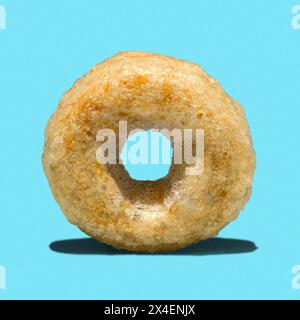 Macro close-up detail of single honey Cheerios cereal isolated on blue with shadow Stock Photo