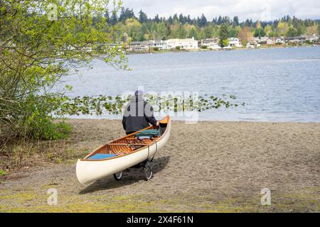 Issaquah, Washington State, USA. Man pulling his canoe on a dolly to transport it to Lake Sammamish. (MR) Stock Photo