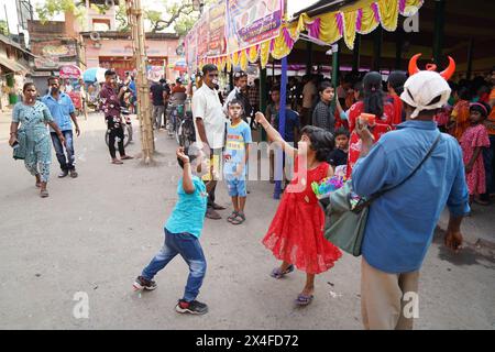 Joyful children dance while a street vendor blows soap bubbles. Bainan Bazaar area, Bagnan, Howrah, West Bengal, India. Stock Photo