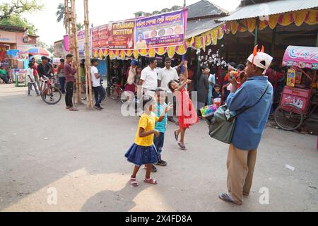 Joyful children dance while a street vendor blows soap bubbles. Bainan Bazaar area, Bagnan, Howrah, West Bengal, India. Stock Photo