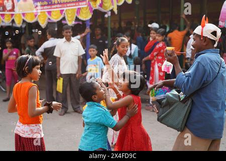 Joyful children dance while a street vendor blows soap bubbles. Bainan Bazaar area, Bagnan, Howrah, West Bengal, India. Stock Photo