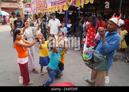 Joyful children dance while a street vendor blows soap bubbles. Bainan Bazaar area, Bagnan, Howrah, West Bengal, India. Stock Photo