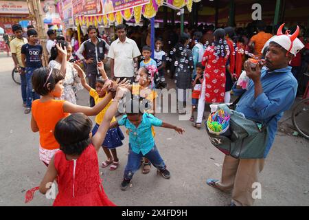 Joyful children dance while a street vendor blows soap bubbles. Bainan Bazaar area, Bagnan, Howrah, West Bengal, India. Stock Photo