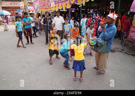 Joyful children dance while a street vendor blows soap bubbles. Bainan Bazaar area, Bagnan, Howrah, West Bengal, India. Stock Photo