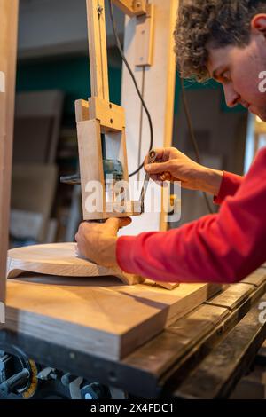Attentive carpenter sets up milling machine. Careful man tightens tool with spanner Stock Photo