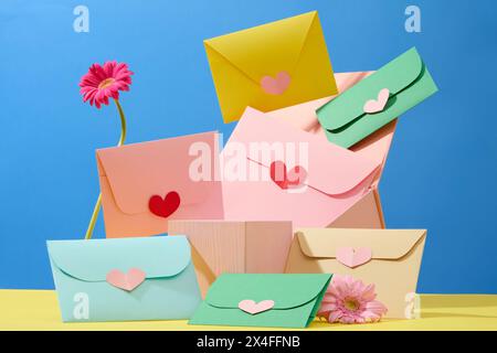 Women's day background with colorful handmade envelopes decorated with fresh gerberas and empty wooden podium on blue background. Front view, space fo Stock Photo