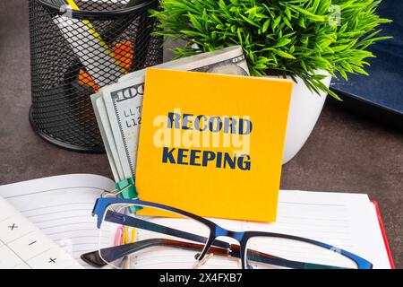 Record keeping text concept on a yellow sticker with dollars, on the desktop of a businessman, manager Stock Photo