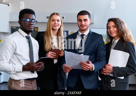 Multiethnic team of corporate professionals gather, smiling African, Caucasian woman, Arabic man, Asian businesswoman in office setting, engaged in Stock Photo