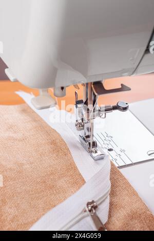 Modern sewing machine with special presser foot makes a seam on grey ...