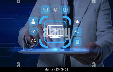 Webinar. Man using tablet on dark blue background, closeup. Virtual screen with icons over device Stock Photo