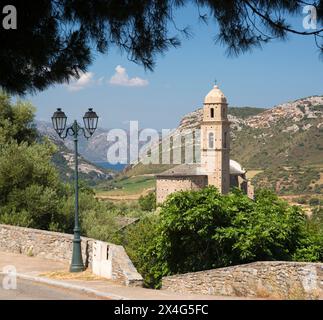 Patrimonio, Haute-Corse, Corsica, France. View across road to the historic Église Saint-Martin and distant Gulf of Saint-Florent. Stock Photo