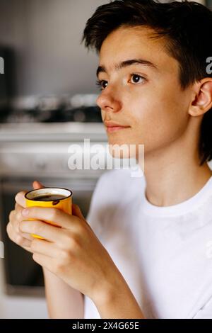 Adolescent with cup of coffee at home. Stock Photo