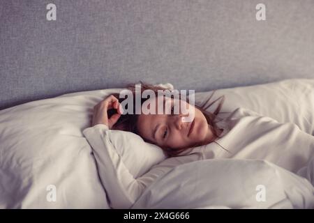 Portrait of young woman lying on bed Stock Photo