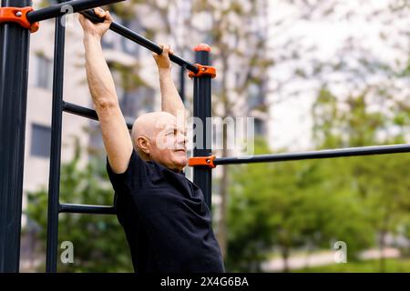 Senior person doing pullups outside Stock Photo