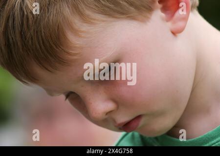 Red-haired boy in deep concentration, immersed in thought Stock Photo