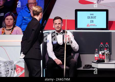 David Gilbert (right) speaks with match referee Tatiana Woollaston during their semi-final match against Kyren Wilson (not pictured) on day fourteen of the 2024 Cazoo World Snooker Championship at the Crucible Theatre, Sheffield. Picture date: Friday May 3, 2024. Stock Photo