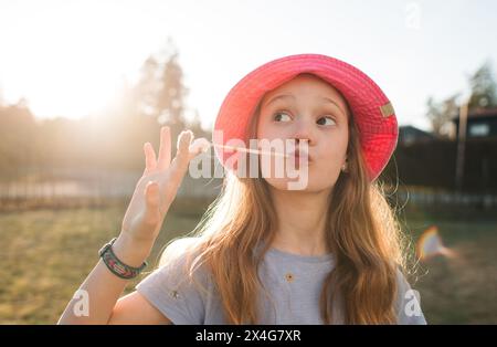 girl playing with bubblegum whilst outside on a summers day playing Stock Photo