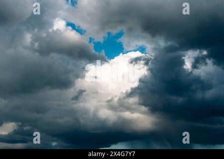 Dark rainy clouds and a small gap of blue sky, background. Stock Photo