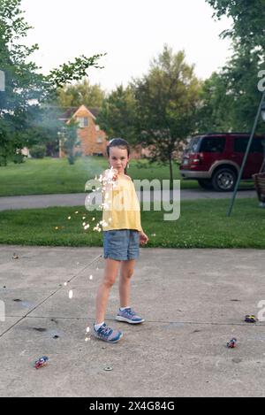 Girl with sparkler on driveway at sunset Stock Photo