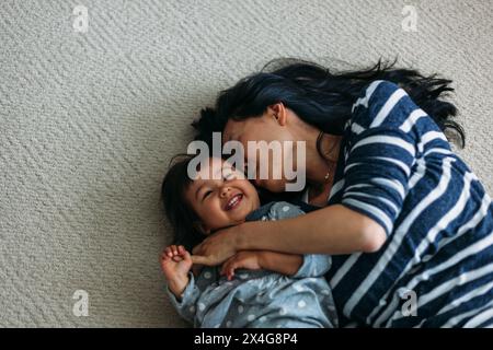 Mother and daughter snuggling on the floor Stock Photo