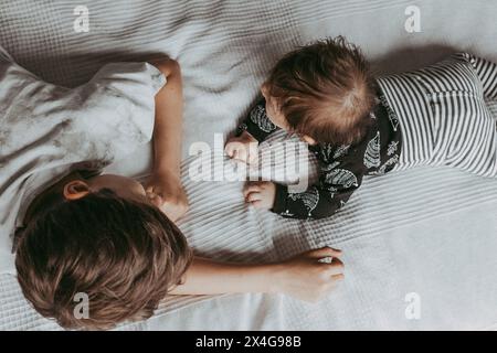 Brothers lay on the bed in bedroom and look at each other Stock Photo
