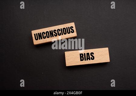 Unconscious bias words written on wooden blocks with black background. Conceptual unconscious bias symbol. Copy space. Stock Photo