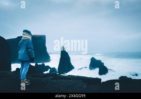 Woman tourist visit famous beach Valhnukamol beach in storm Icelandic weather conditions on west atlantic coast in Iceland Stock Photo