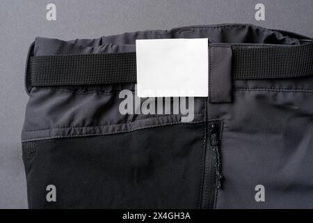 Cardboard label attached to the waistband of dark gray outdoor trousers Stock Photo
