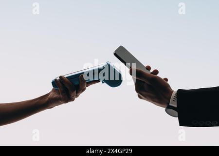 Electronic device held by hands on background studio. Hands scan bill with card reader for contactless payment using a mobile banking app. Stock Photo
