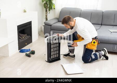 young man changing - fixing a dirty air purifier HEPA filter after using for a long time. A repairman replacing and installing the air purifier filter Stock Photo