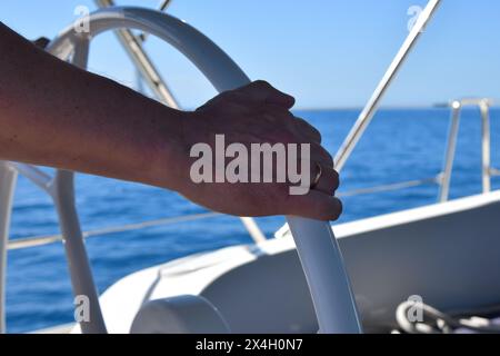 Man hand on yacht steering wheel on sailboat cockpit. Yacht helmsman. Yachting Stock Photo