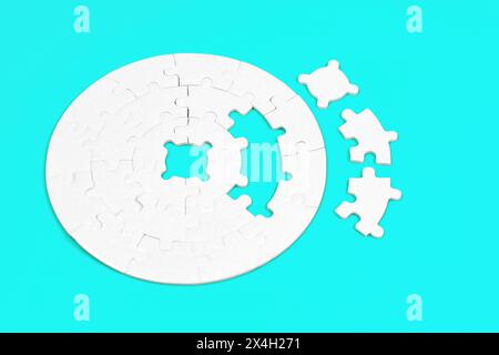 Blank round jigsaw puzzle and three final pieces set aside on a light blue background. Stock Photo