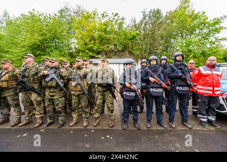 03 May 2024, Rhineland-Palatinate, Kirchheimbolanden: Bundeswehr soldiers, police forces and paramedics from the German Red Cross stand together during the exercise. The Rhineland-Palatinate State Command is conducting an exercise with the Rhineland-Palatinate and Hunsrück homeland security companies on the site of the former ammunition depot near Kriegsfeld (Donnersberg district), which is to be reactivated by 2028. During the Bundeswehr exercise National Guardian, part of the Bundeswehr exercise series QUADRIGA, homeland security forces throughout Germany practise their core mission of prote Stock Photo