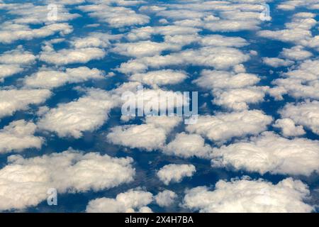 Oblique angle looking down on scattered white fluffy cumulus clouds over land, Europe Stock Photo
