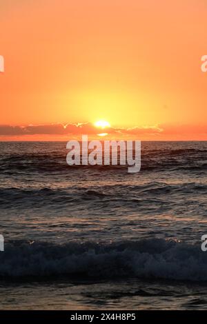 golden sunset casting a warm glow over the sea, with the sunlight reflecting on the gentle waves, creating a peaceful and mesmerizing view Stock Photo