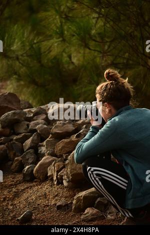 passionate about photography, a young woman documents the serene natural environment, focused on capturing perfect moments Stock Photo