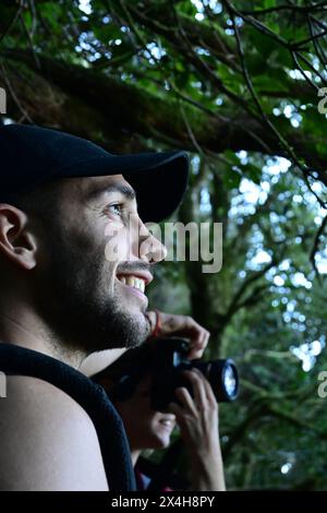 nature's admirer: profile portrait of a young man smiling as he admires the natural beauty around him, with sunlight illuminating his face in a lush f Stock Photo