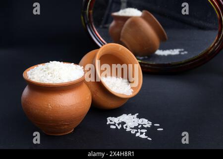 rice grains in the clay pot. traditional mud pot vessel to preserve or cook rice. Also have refclation from mirror. Stock Photo