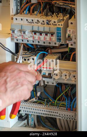 an electrician works on a fuse box Stock Photo