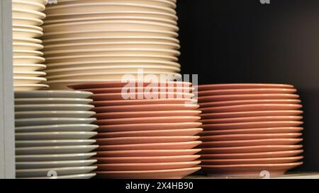 Ceramics porcelain multicolored plates on the shelf. Open space area. Selective focus. Stock Photo