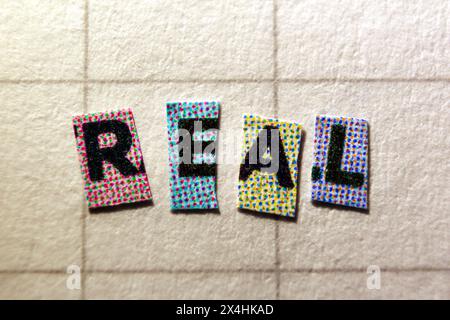 Cut-out letters forming the word real, macro closeup Stock Photo